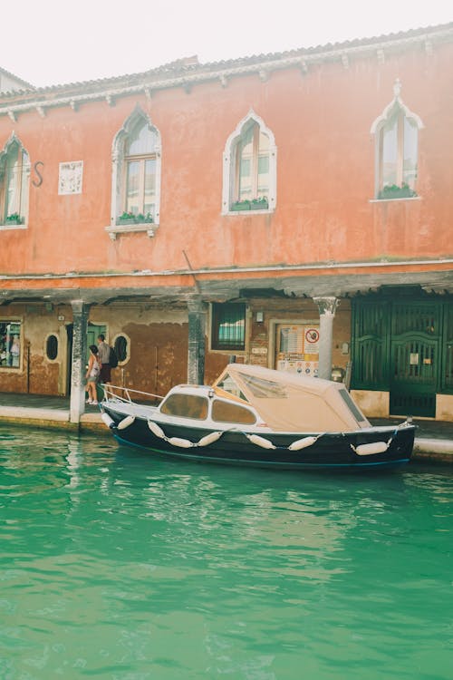 Boat on Water Near Brown Concrete Building