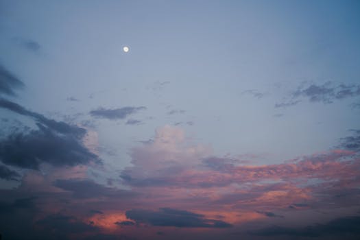 黄昏的天空宁静，月亮与彩云相伴