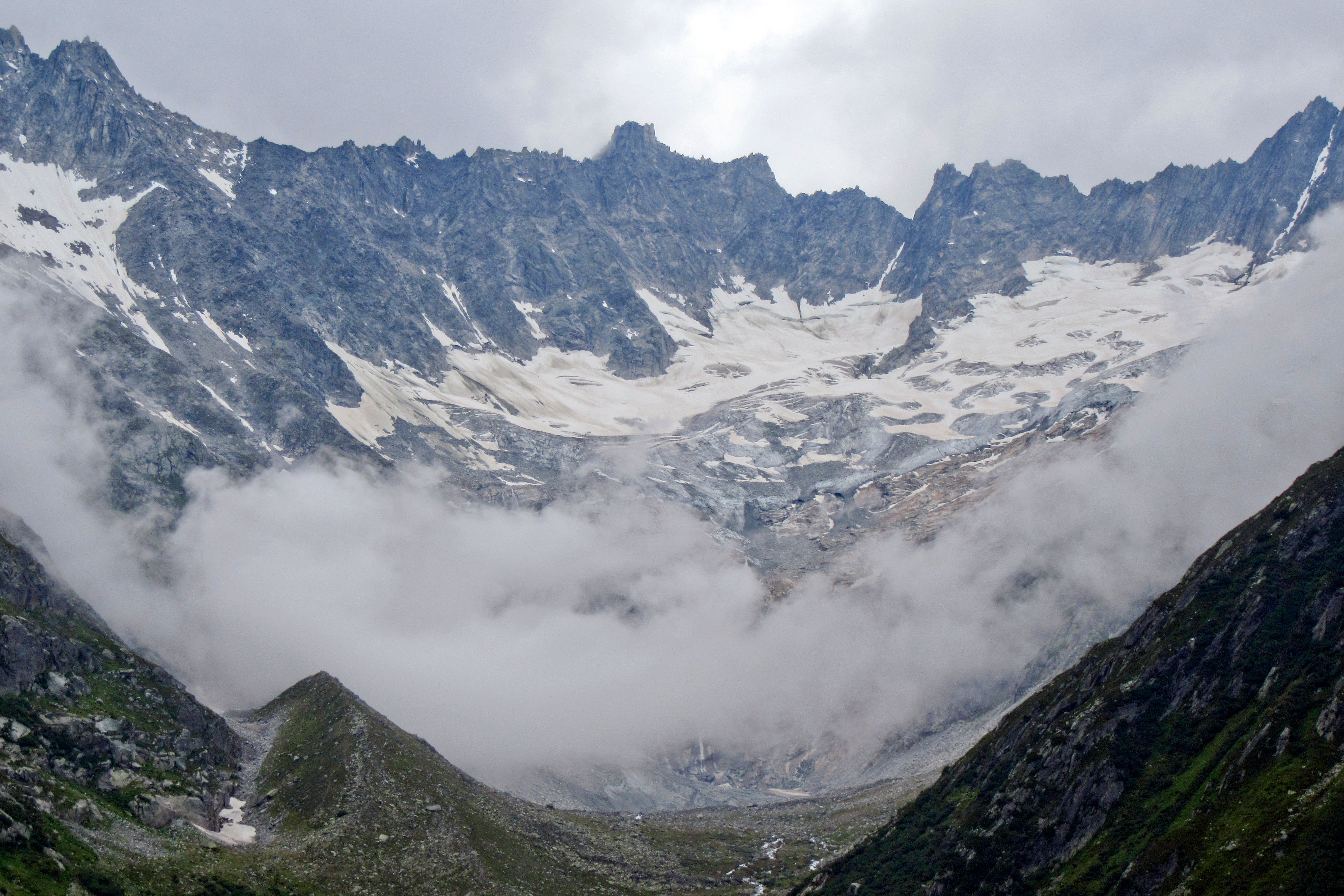 Breathtaking view of snowcapped mountains with glacier and clouds. A serene winter landscape.