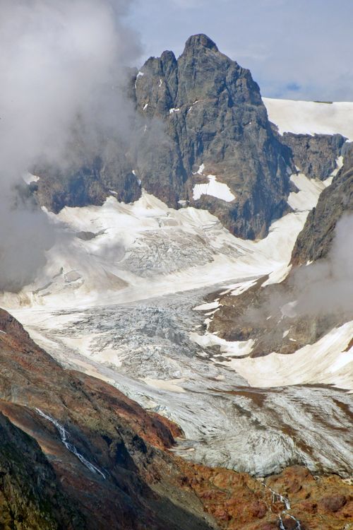 Free Breathtaking view of a rugged mountain and glacier enveloped by clouds. Stock Photo