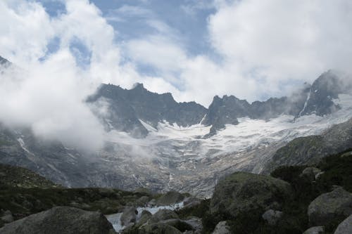 Breathtaking scenery of mountain ridge covered with snow surrounded by clouds at daytime