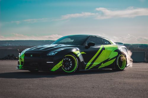 Free Modern tuned sports car with tinted windows drifting on asphalt road against cloudy blue sky Stock Photo