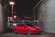 Shiny red car near shabby buildings at night
