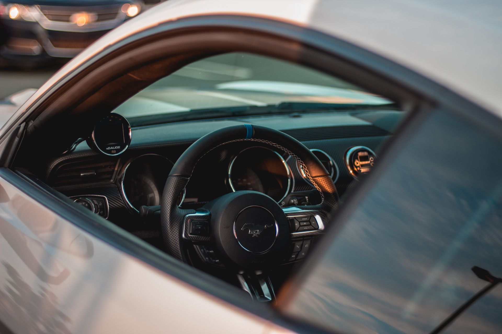 High angle of steering wheel and dashboard of contemporary white shiny car parked on street on sunny day
