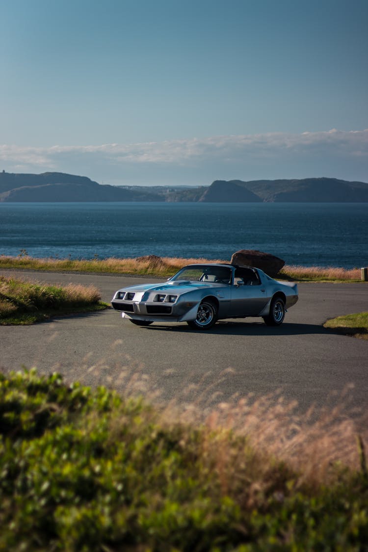 Retro Sports Car On Even Asphalt Road Between Meadow And Lake