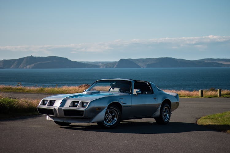 Vintage Sports Car Parked On Paved Road Near Coast Of Lake