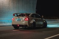 Sports car riding on road under bridge at night