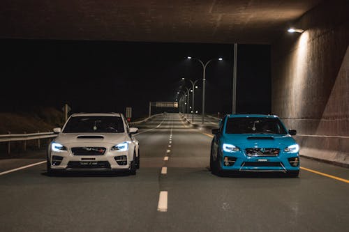 Blue and white sports car riding on empty road at night