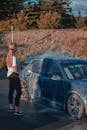 Faceless slender woman washing automobile at car wash