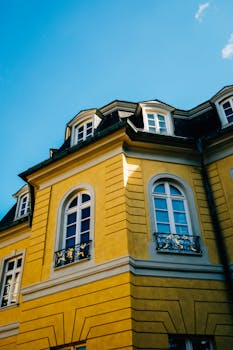 A classic yellow building facade with ornate details under a clear blue sky, emphasizing historical architecture.