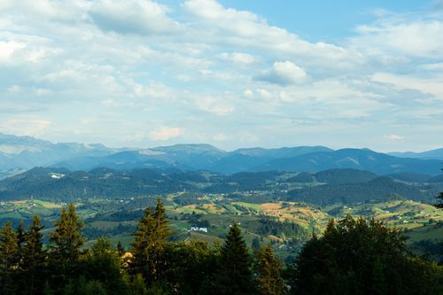 Free Panoramic view of Romania's lush summer mountains and green valleys under a clear blue sky. Stock Photo