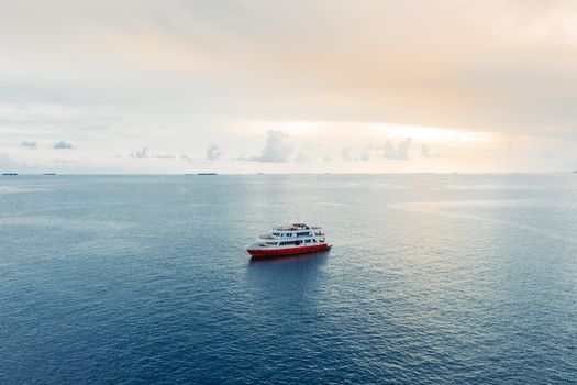 Picturesque view of cruise ship floating on blue rippling seawater under light pink sky at twilight