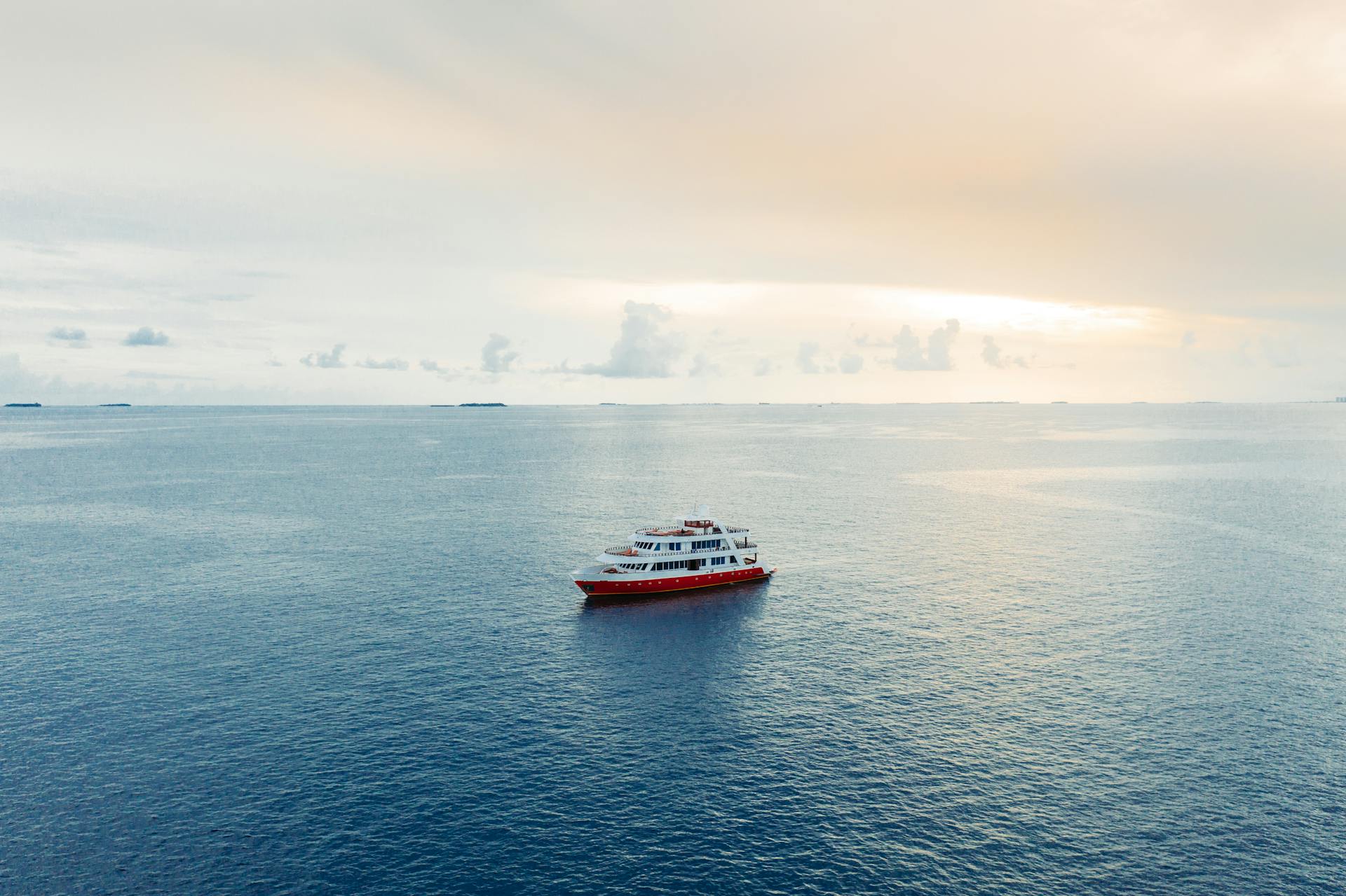 Picturesque view of cruise ship floating on blue rippling seawater under light pink sky at twilight