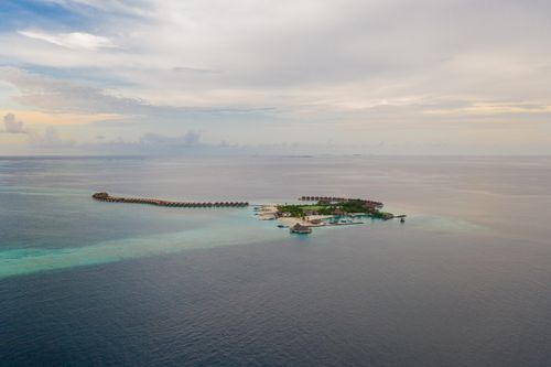 Free Drone view of small tropical island with peaceful resort surrounded by endless blue sea on clear weather Stock Photo