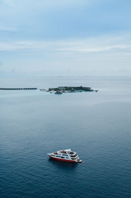 Drone view modern cruise ship floating on endless rippling sea near small tropical island on clear weather