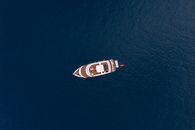 Drone top view contemporary yacht floating on dark blue rippling sea on cam windless day