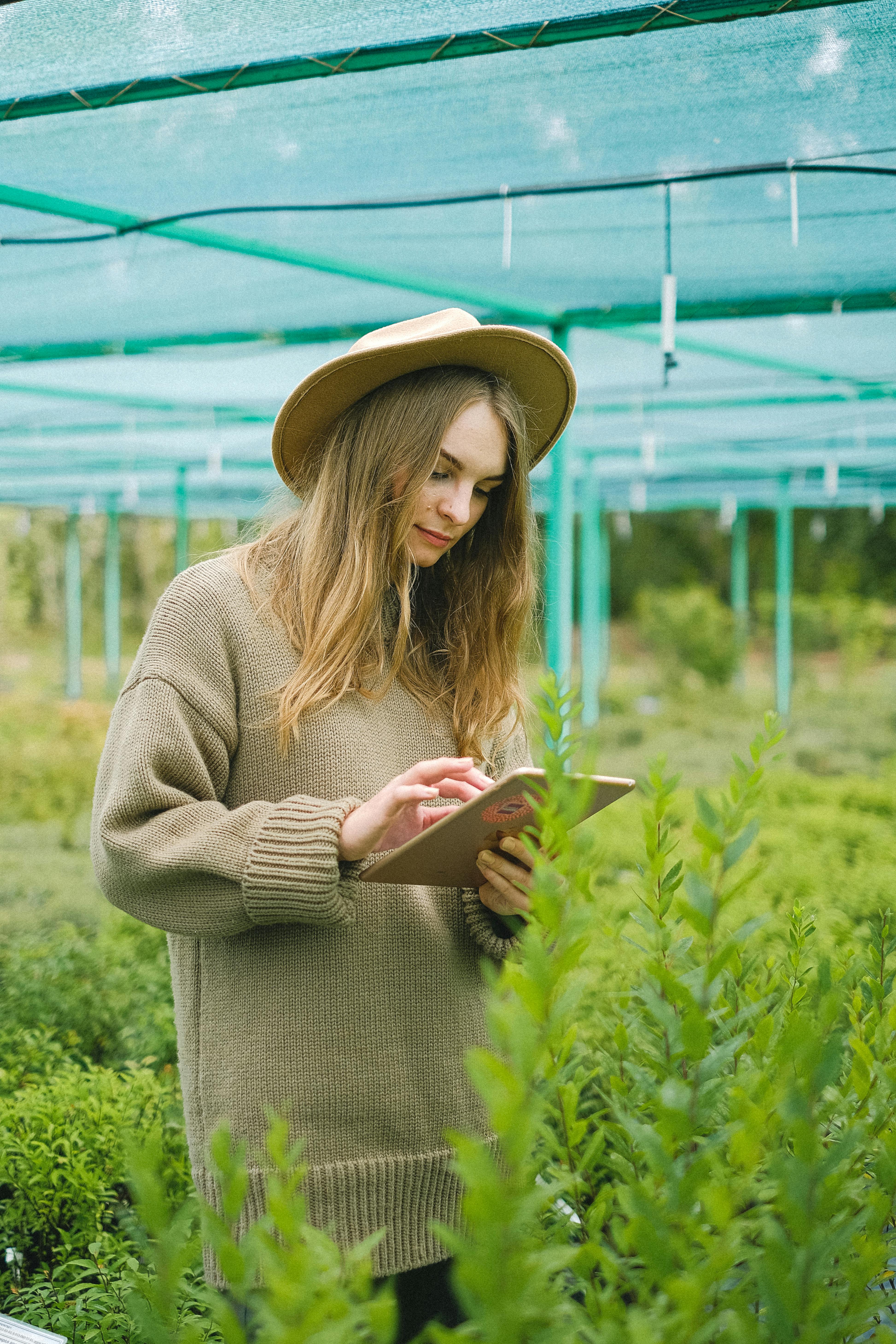 young female gardener browsing tablet for work in farm