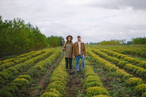 Couple with farm tools standing in field