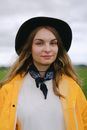 Woman in hat and bandana on neck standing in nature