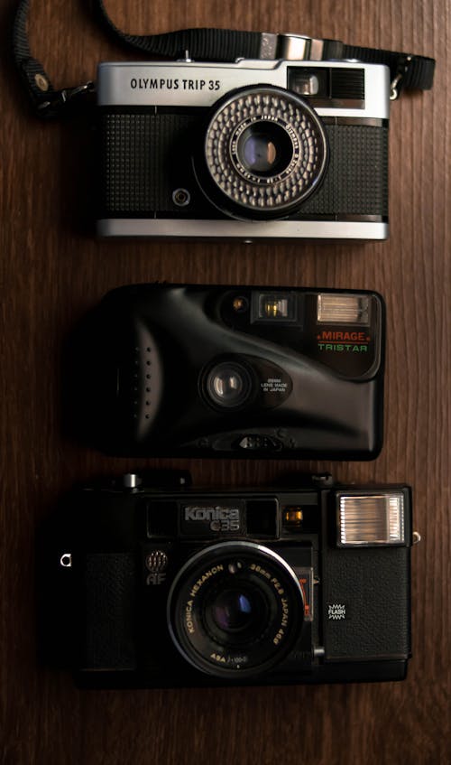 Top view of collection of vintage film cameras with optical lenses arranged on wooden table