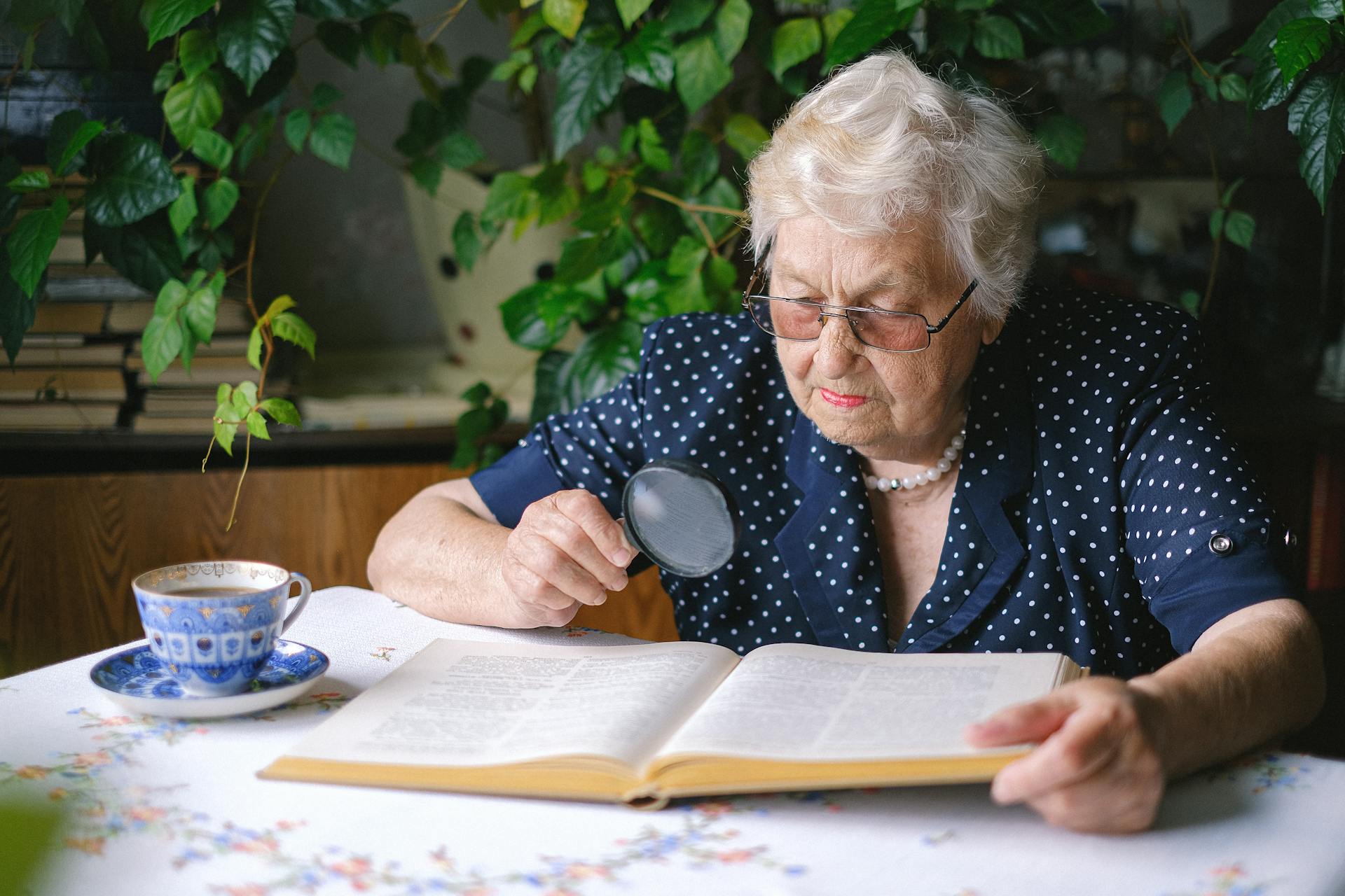 Focused senior woman reading with magnifier