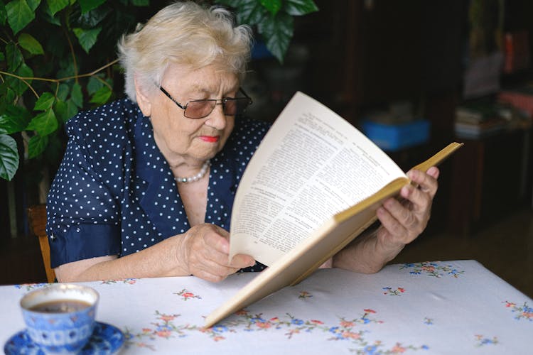 Focused Aged Woman Turning Pages Of Book