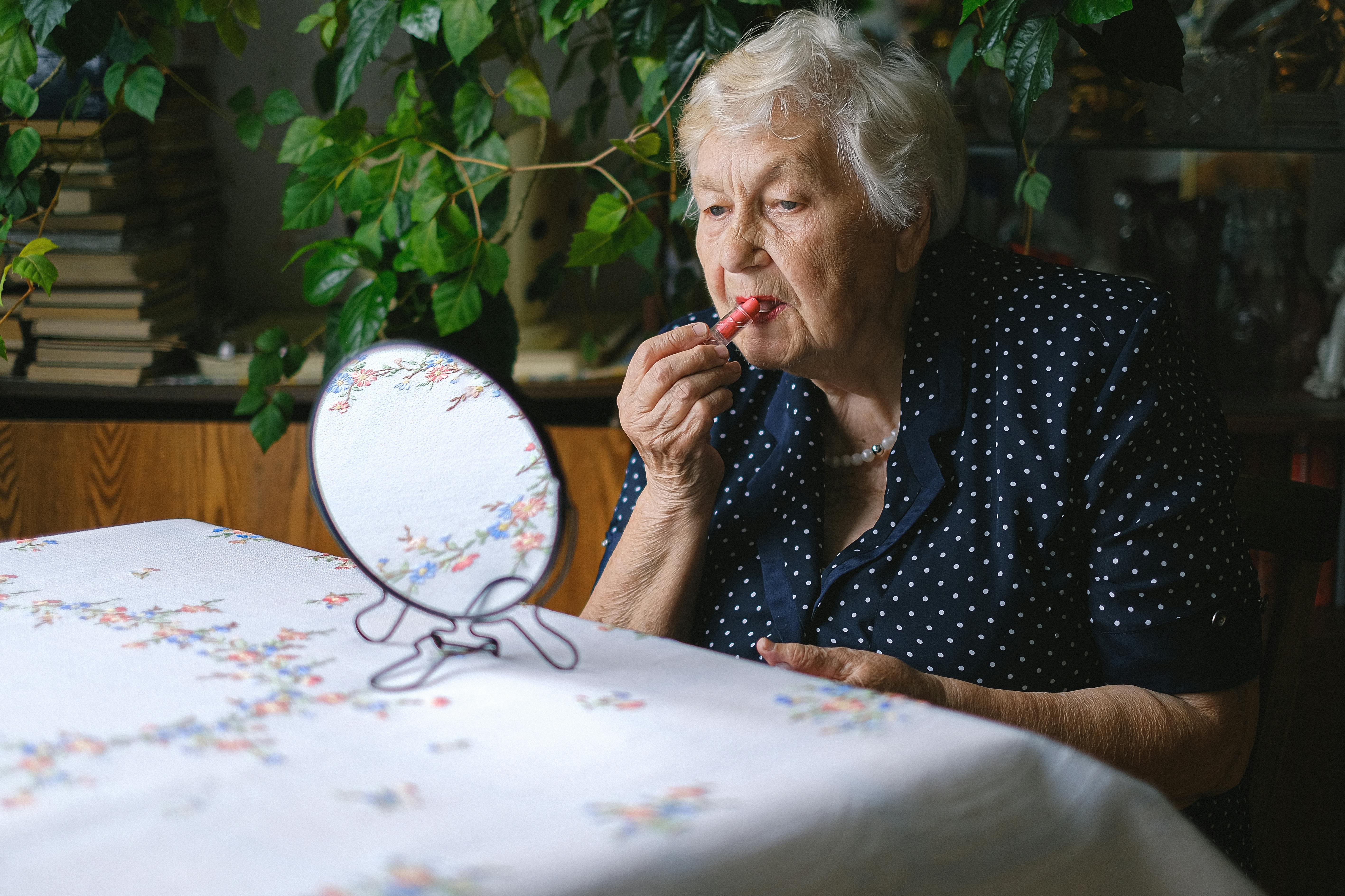 elderly woman doing makeup in home