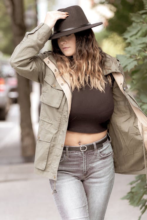 Young female with long hair looking down on blurred background of street in daytime