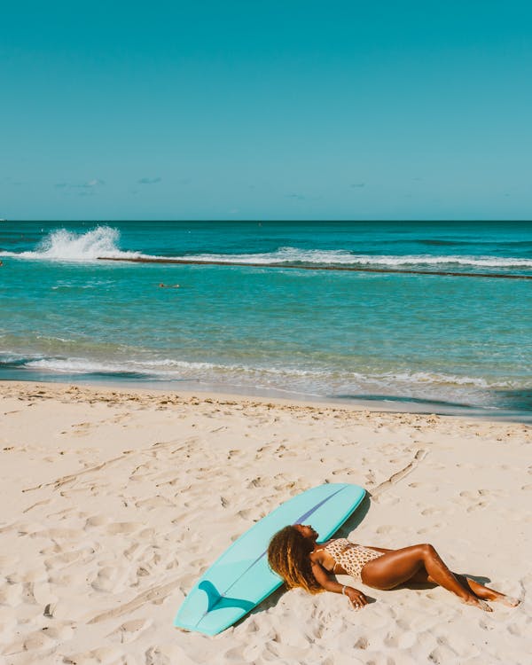 Woman in Blue Bikini Lying on White Sand Beach