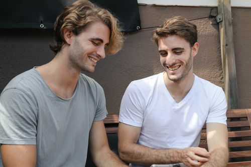 Free Two friends enjoying a moment of laughter together while seated outdoors in Barcelona. Stock Photo