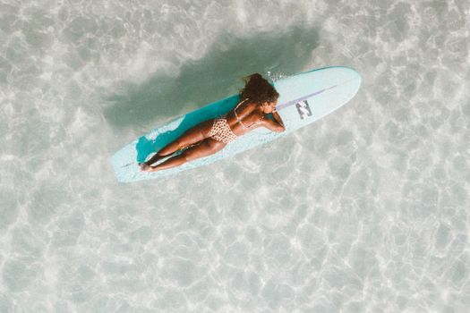 A Woman Resting on a Floating Surfboard