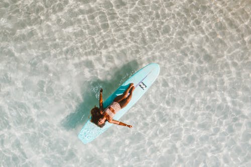 A Woman Resting on Her Floating Surfboard