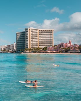 An inviting hotel by a tropical beach with surfers enjoying the summer waves.