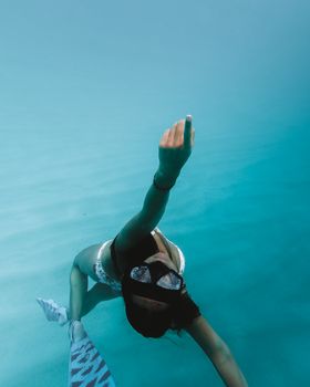 一名女子在清澈蔚蓝的大海中浮潜，她戴着护目镜和脚蹼，营造出宁静的水上场景