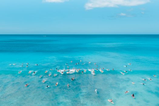 晴朗的夏日天空下，碧绿海洋上众多冲浪者享受冲浪的鸟瞰图