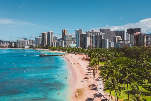 Free Stunning aerial view of Waikiki Beach with turquoise water and the bustling Honolulu skyline under a clear blue sky. Stock Photo