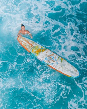 Aerial shot of a smiling woman surfing in vibrant blue ocean waters.