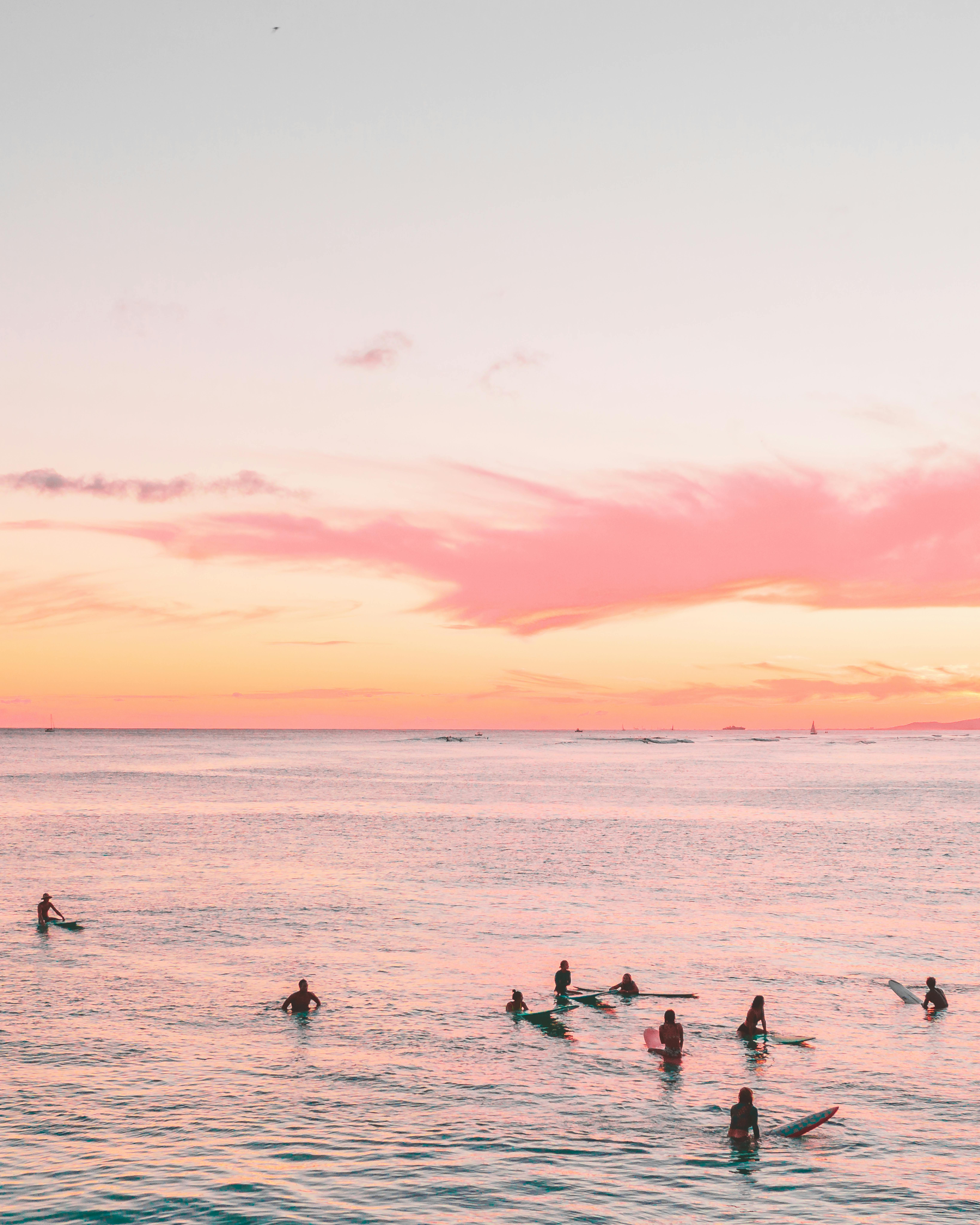 冲浪者在平静的海水中享受宁静的日落，创造出风景如画的海滩景观
