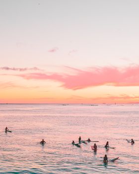 冲浪者享受着平静海水中的宁静日落，构成了一幅风景如画的海滩景观