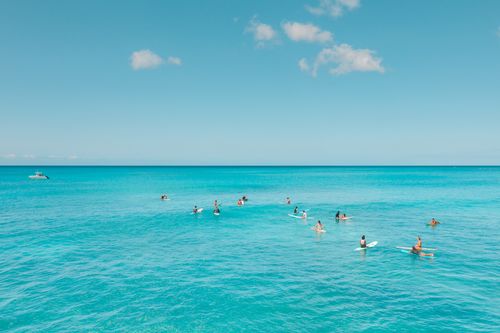 Free Aerial view of surfers enjoying the ocean under a clear blue sky. Stock Photo