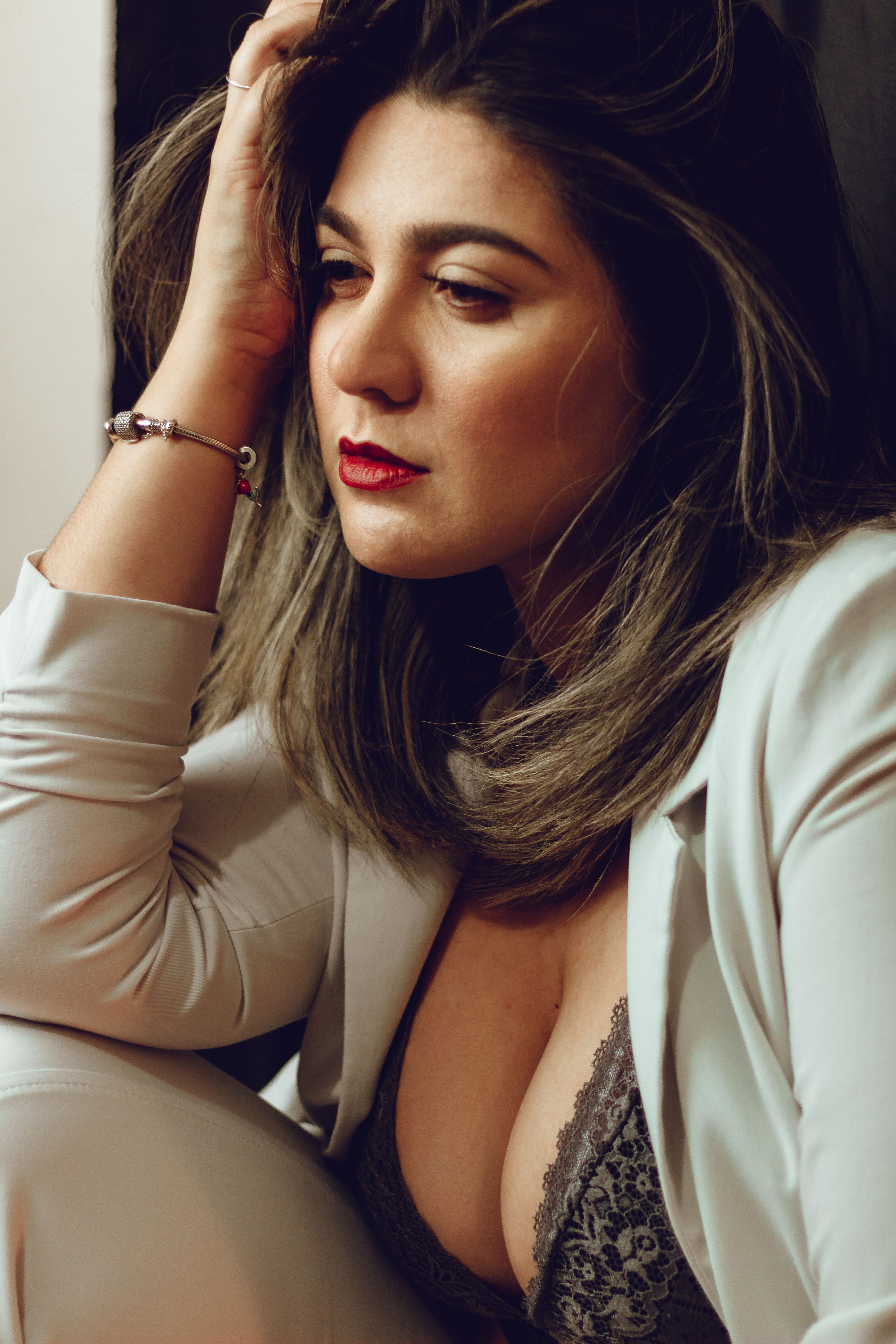 Elegant portrait of a woman in a fashionable pose with red lips and contemplative expression.