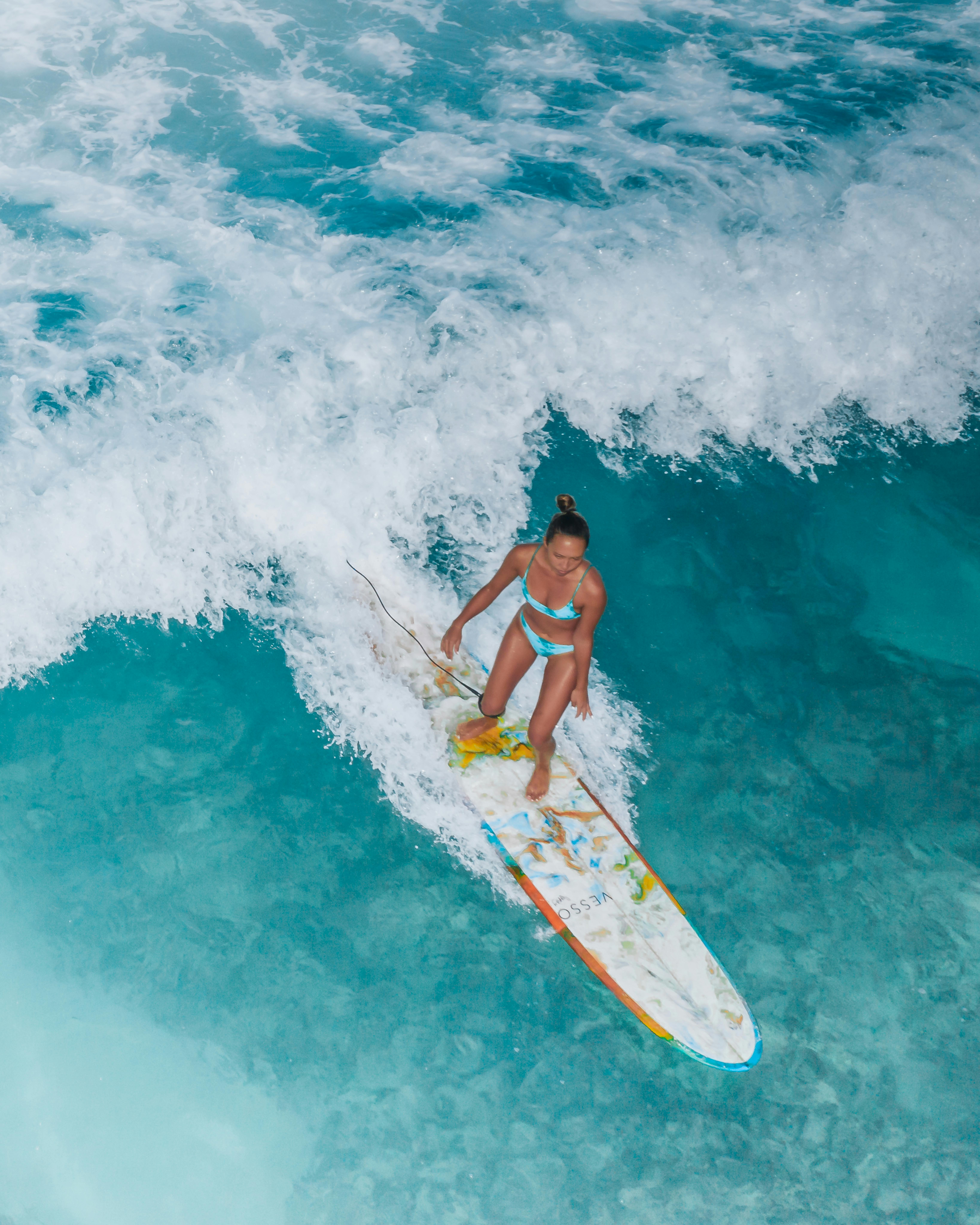 一名女子在充满活力的海浪中冲浪，画面从上方拍摄