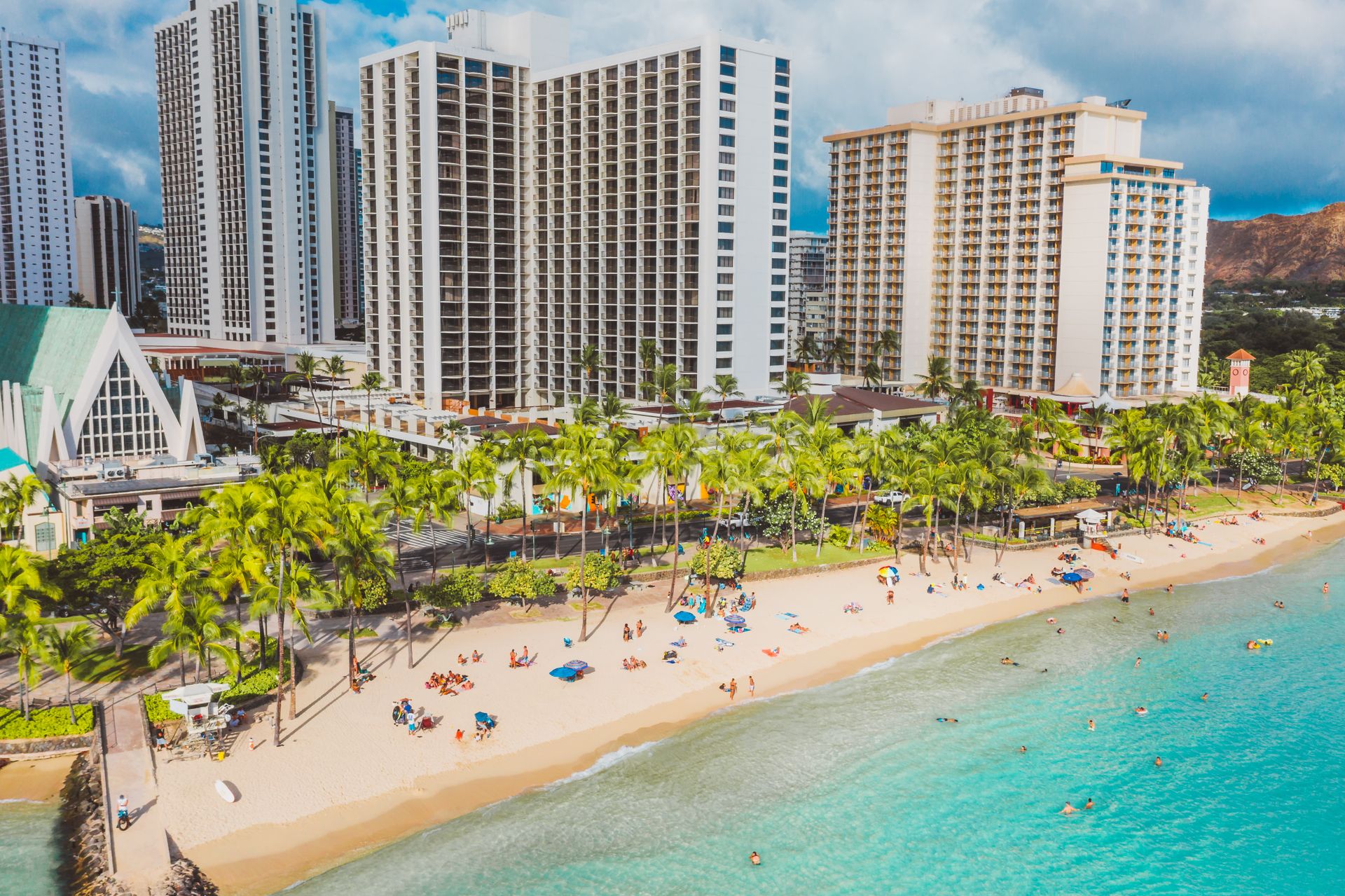 Beautiful aerial view of Waikiki beachfront with hotels and vibrant beachgoers enjoying the summer sun.