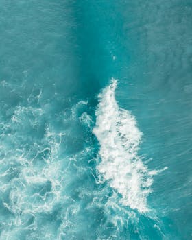 A serene aerial shot of blue ocean waves and sea foam, showcasing natural beauty and tranquility.