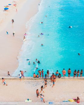A lively beach scene captured from above, featuring people enjoying sun and sea.