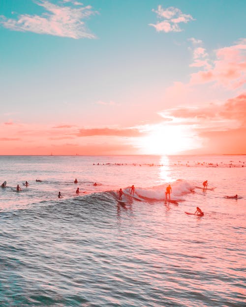 People Surfing on a Sea Waves during Sunset 