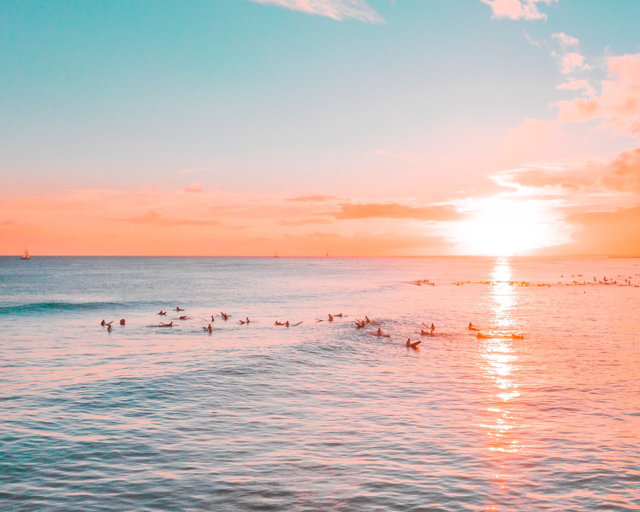 silhouetted surfers catching waves during a stunning sunset over the o