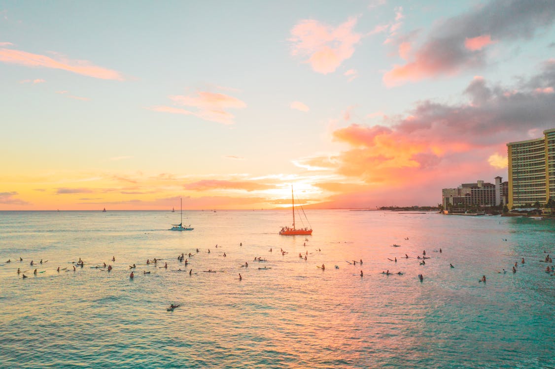 Boats and People Surfing on Sea during Sunset