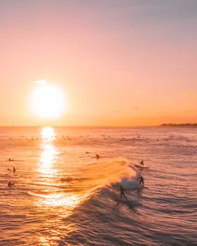 夕阳西下，海面波光粼粼，冲浪者乘风破浪，构成一幅壮丽的海景