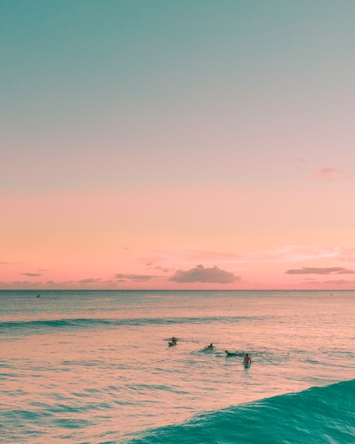 Free Surfers enjoying a tranquil sunset on the ocean, a perfect summer scene. Stock Photo
